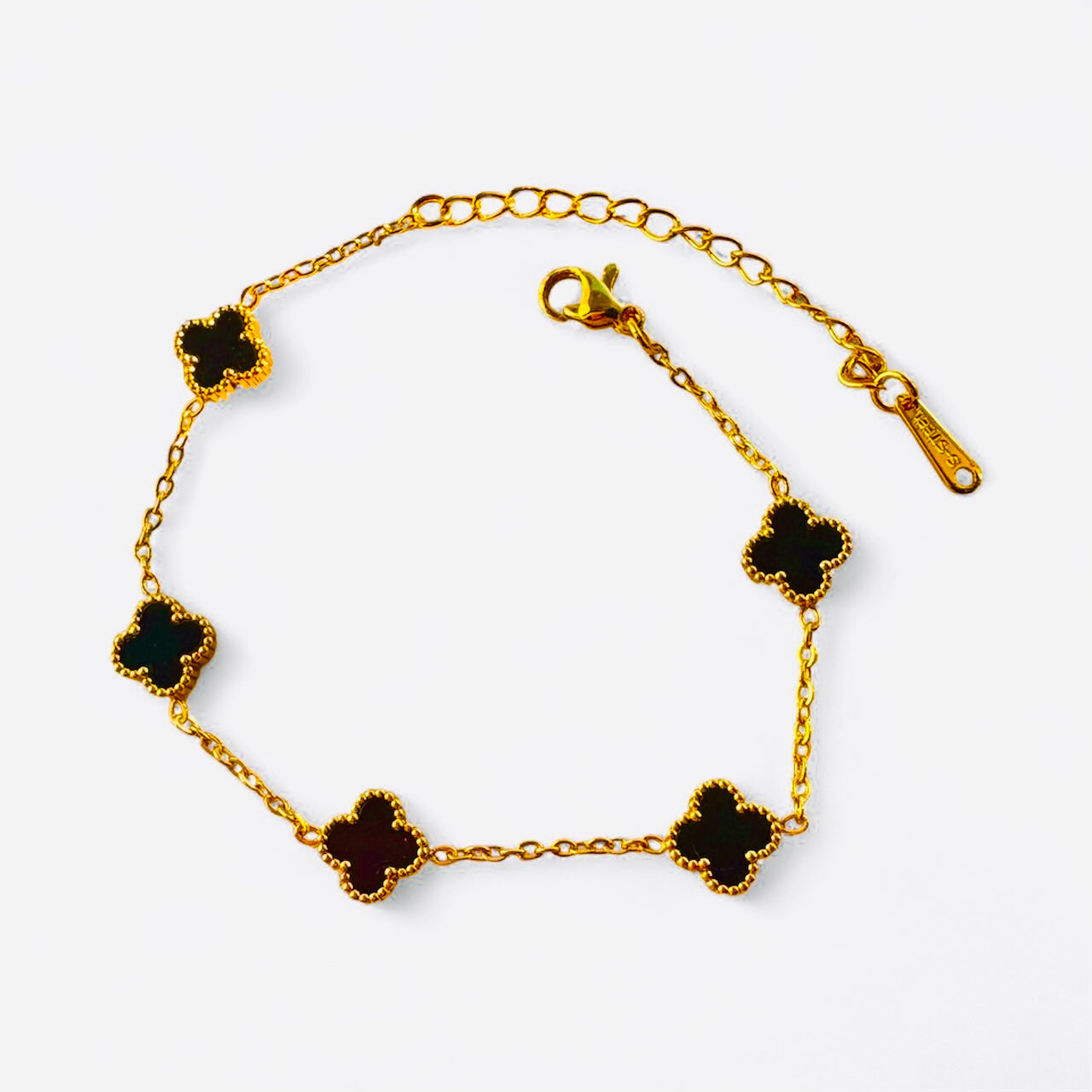 Gold bracelet with black clover-shaped charms on a white background