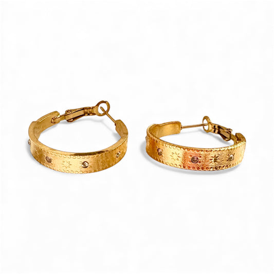 Front view of engraved gold hoop earrings with starburst and dot pattern