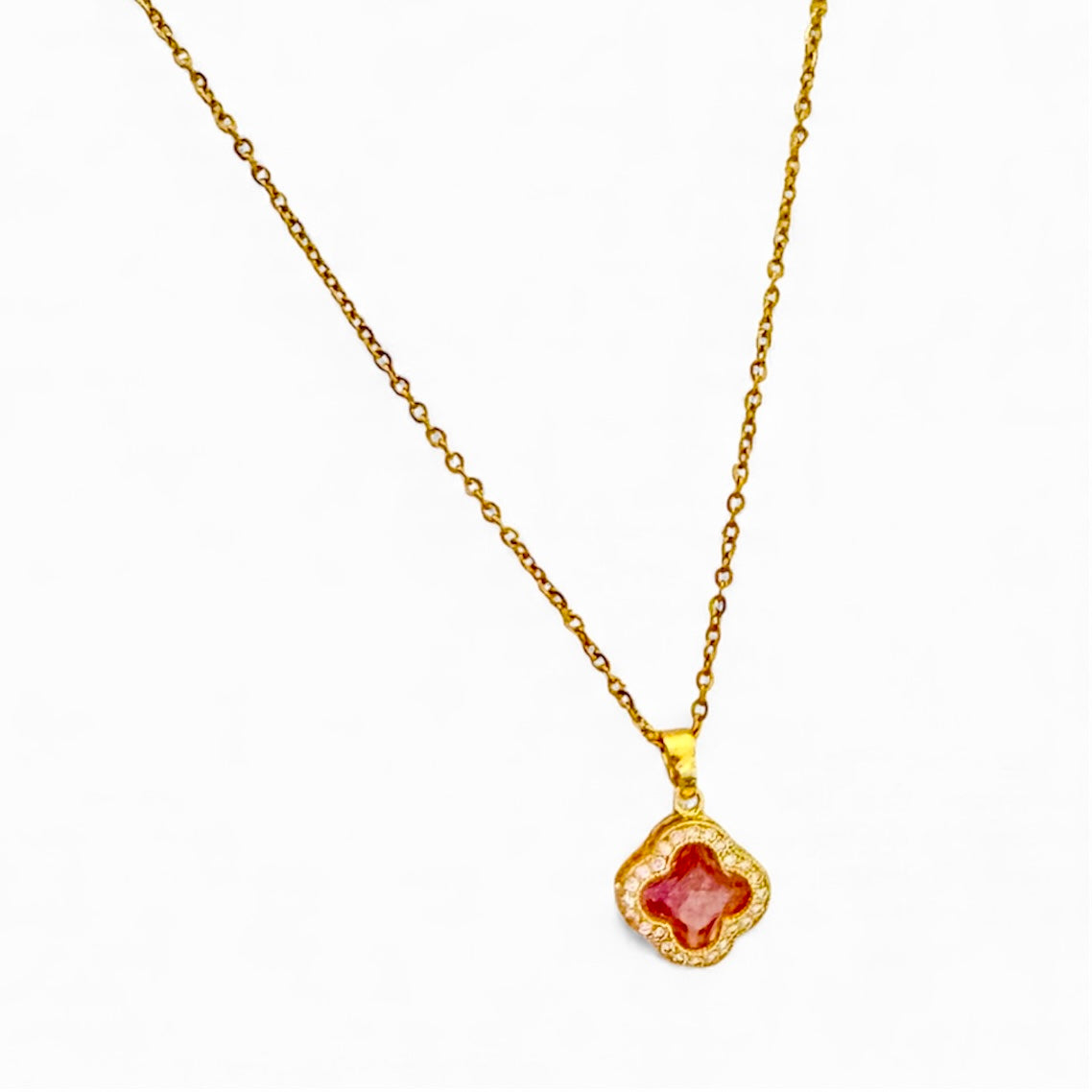 Gold necklace with a red gemstone pendant on a white background