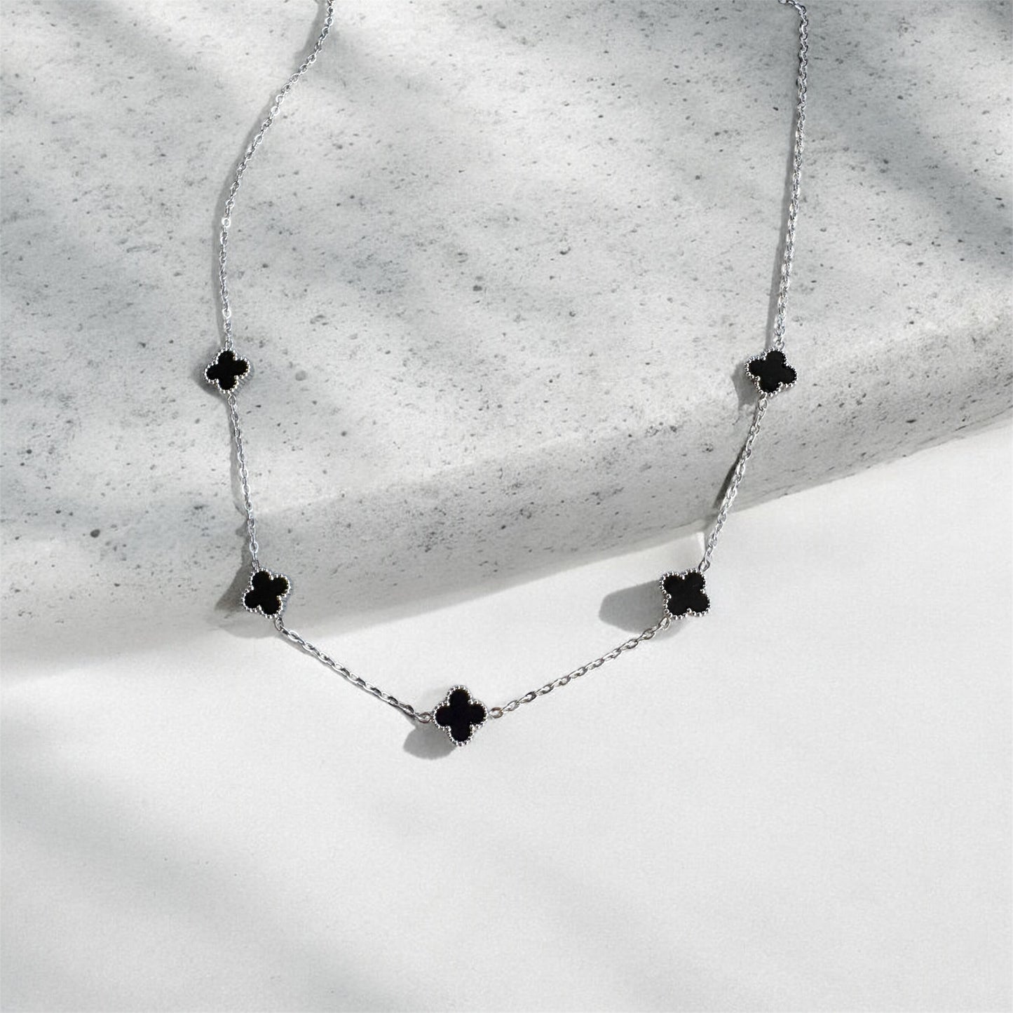 Necklace with black flower-shaped pendants on a textured surface