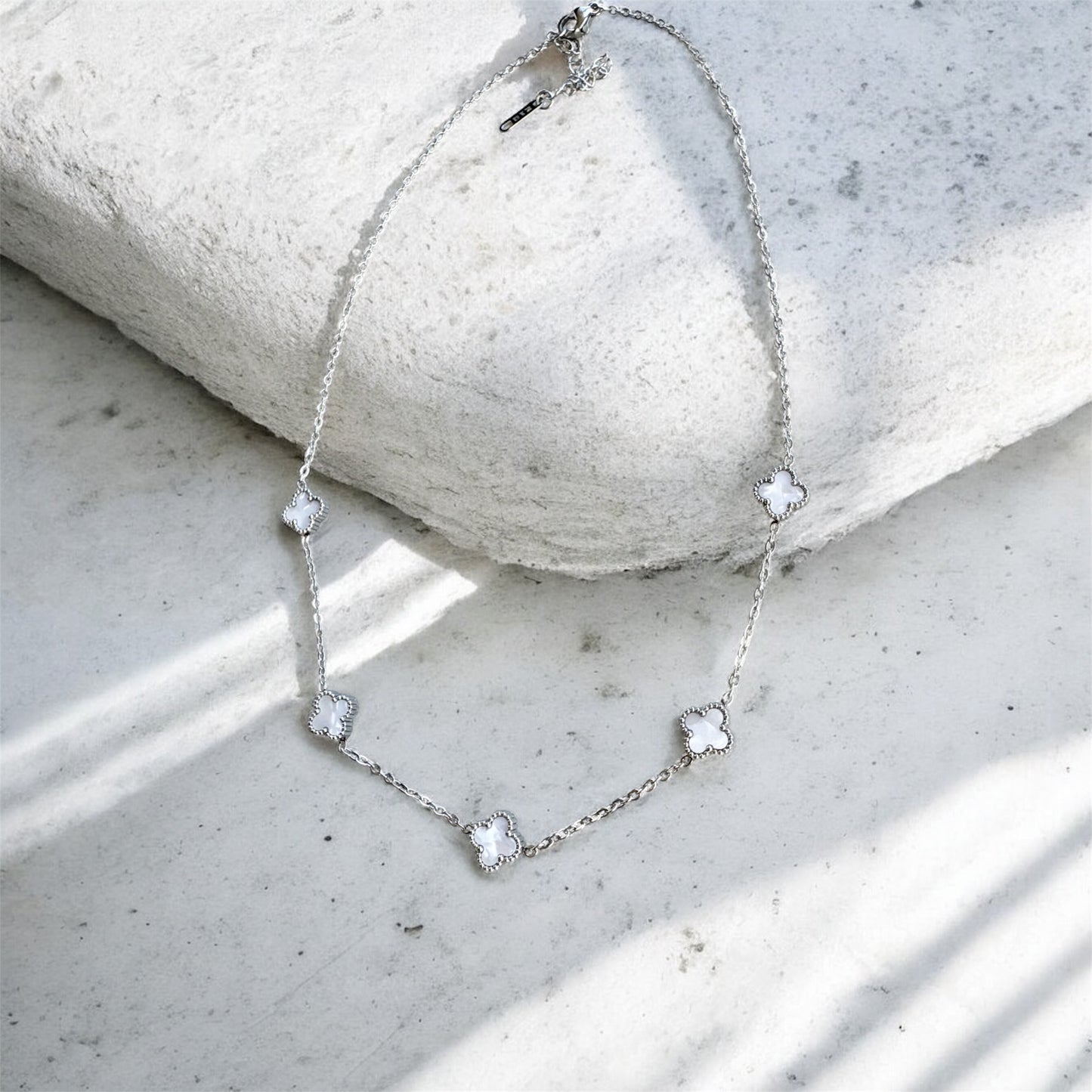 Silver necklace with heart-shaped pendants on a light stone surface