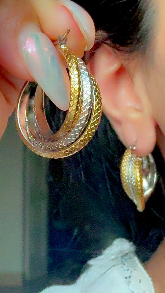 Two-tone gold and silver textured hoop earrings displayed on ear