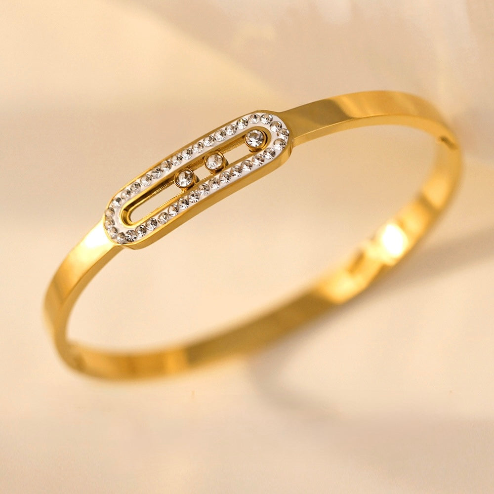 Gold bracelet with a decorative clasp on a beige background