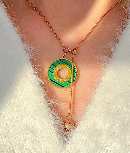 Necklace with a green and gold pendant on a mannequin