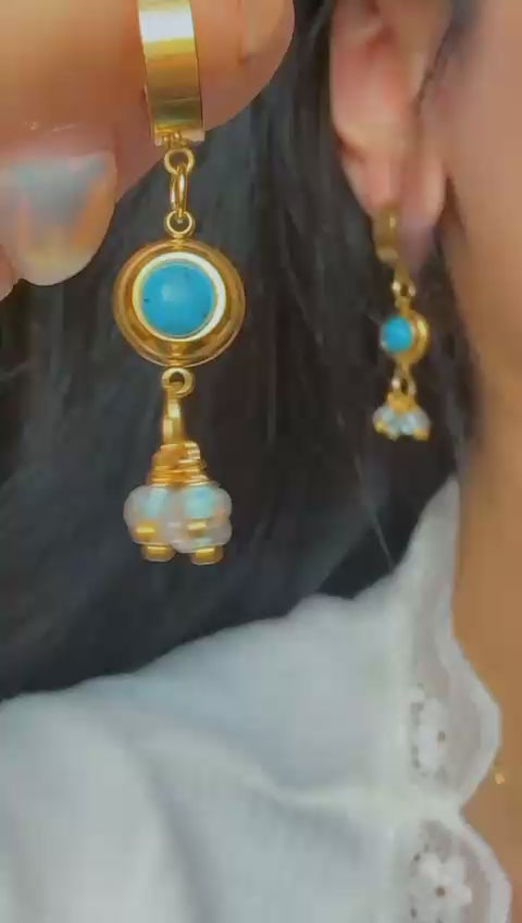 Close-up of turquoise and crystal drop earrings with gold hoop design