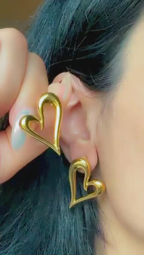 Gold open heart statement earrings displayed on ear